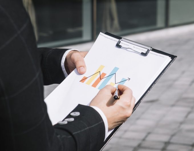 zakonczenie-biznesowej-osoby-reka-rysuje-wzrastajaca-strzala-na-wykresie-nad-schowkiem